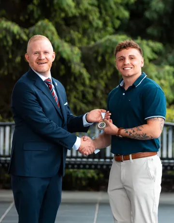 President Young presents an academic award to graduate Jacob Canada.