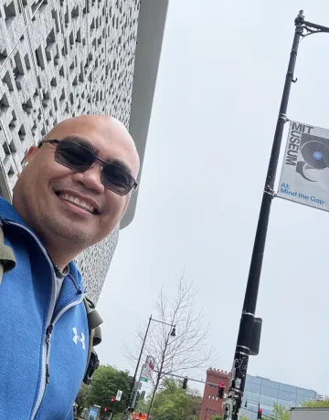 Cumberlands Cybersecurity Professor Elyson De La Cruz takes a selfie in a cityscape. 