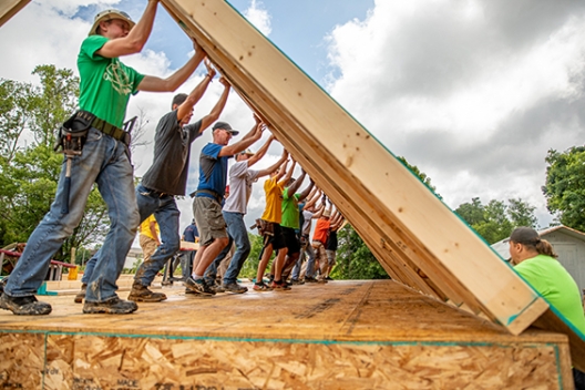 Volunteers help set a wall on a MO house