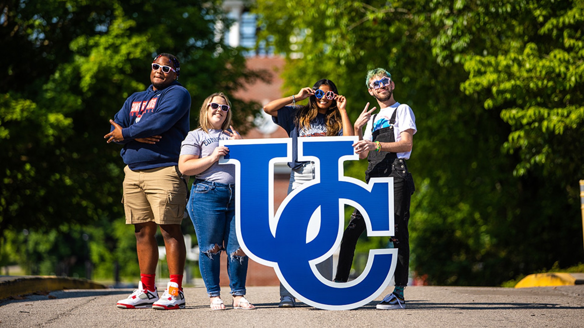 Students pose with sunglasses and UC sign