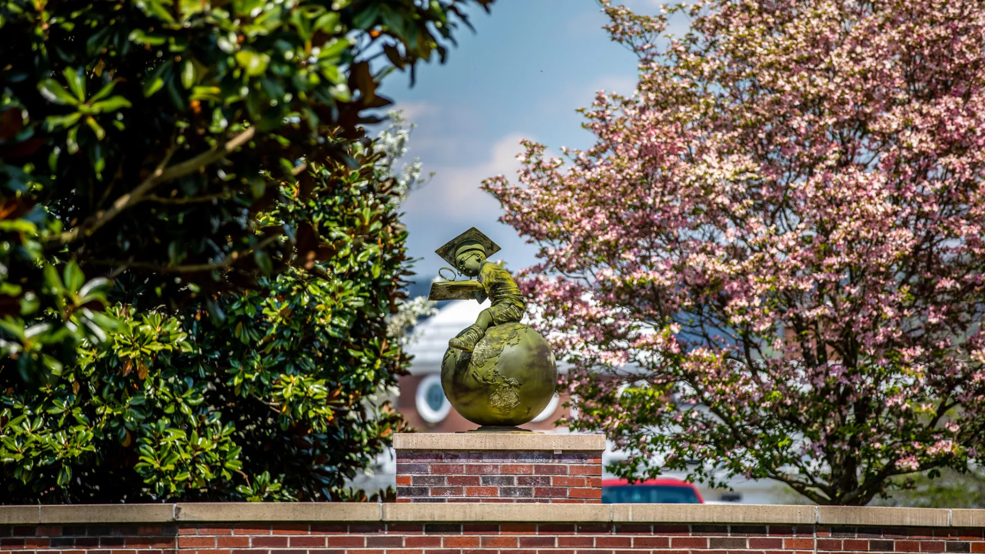 Bronze statue of a boy studying while seated on a globe