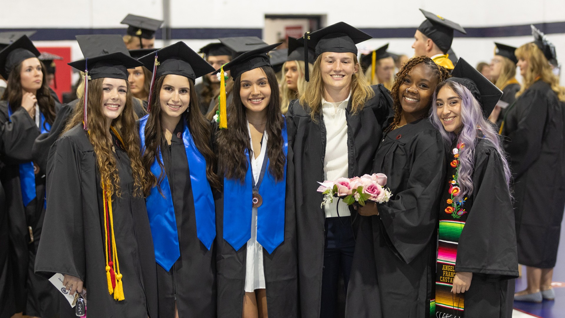 Six female graduates pose in cap and gown following the commencement service. 
