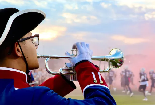 man playing trumpet at a fotball game