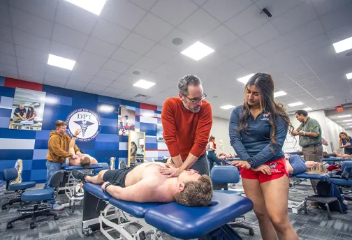 A DPT instructor shows a student proper techniques in the classroom. 