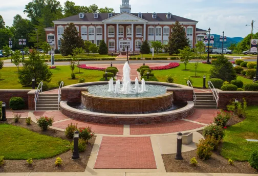 A water fountain in the middle of the college campus. 