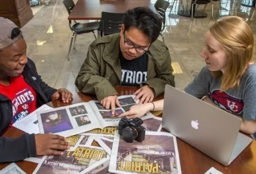 Three people sitting while looking at Newspapers