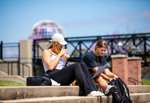 Two students relax near the campus center. 