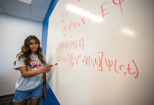 Student explains math equation on whiteboard