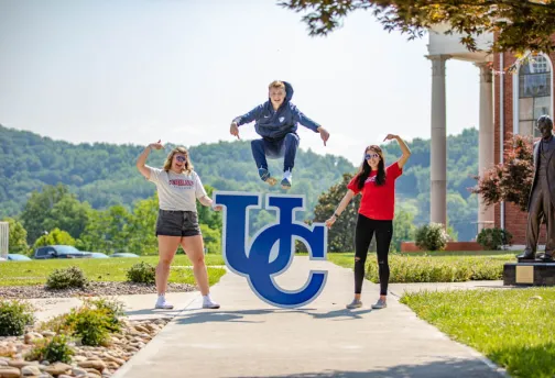 Student leaping over UC sign