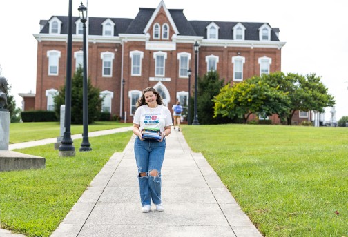 A student poses with books in front of Roburn Hall
