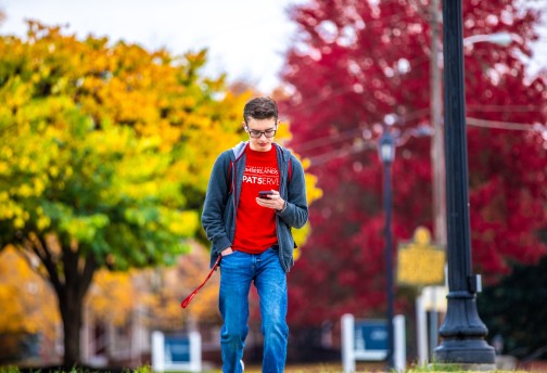 A student looking at their phone while walking