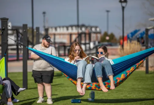 Friends reading while sitting in a hammock