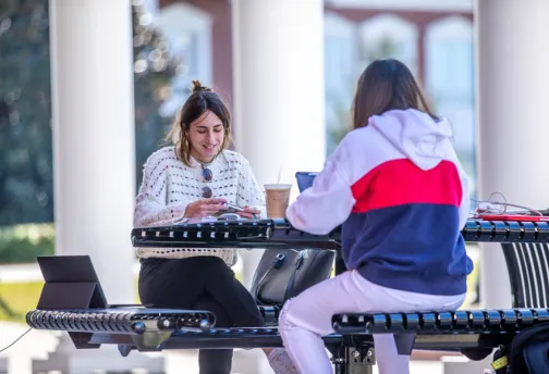 Two girls studying outdoors on campus.