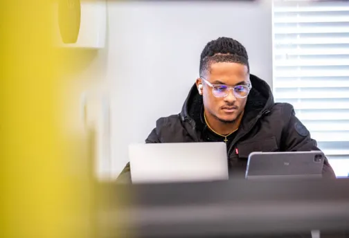 A student using a laptop indoors. 