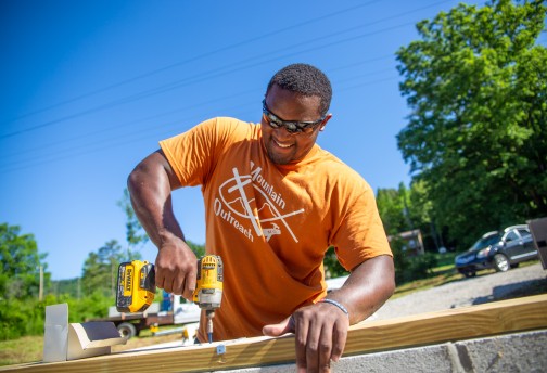 A Mountain Outreach volunteer works on a new home