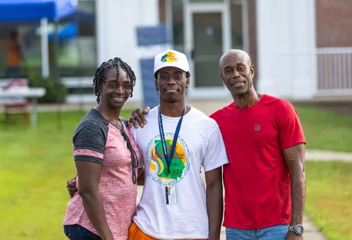 Parents standing with son, posing for picture.