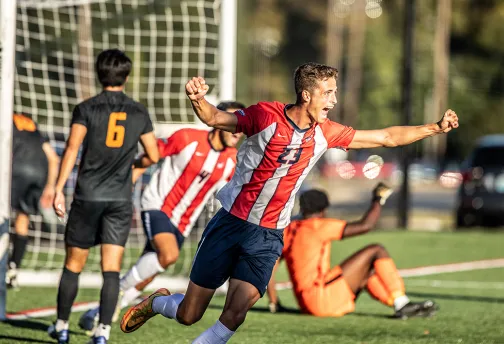 Men's soccer players cheer after scoring a goal