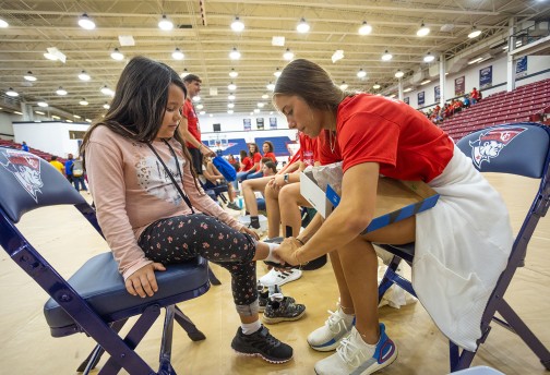A Cumberlands student helps a local child try on new shoes
