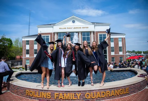 Students celebrate near the fountain during graduation