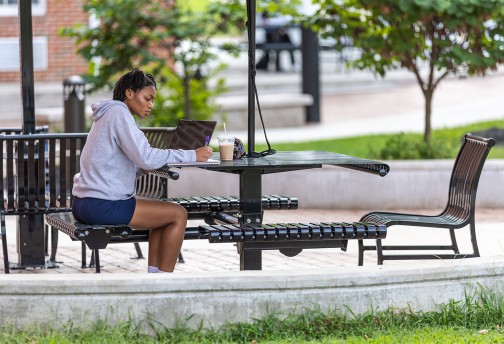 A student sits outside in the quad doing coursework 
