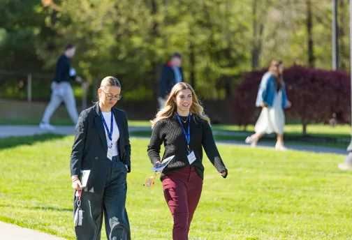 Two female business students walk across campus during the annual business forum. 