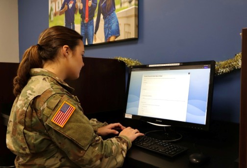 A female ROTC student works on a computer in an office. 