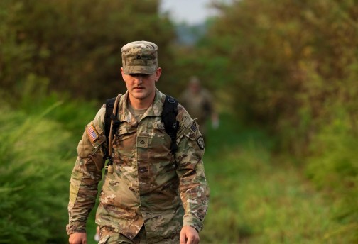 A male National Guardsman leads ROTC students on a ruck. 