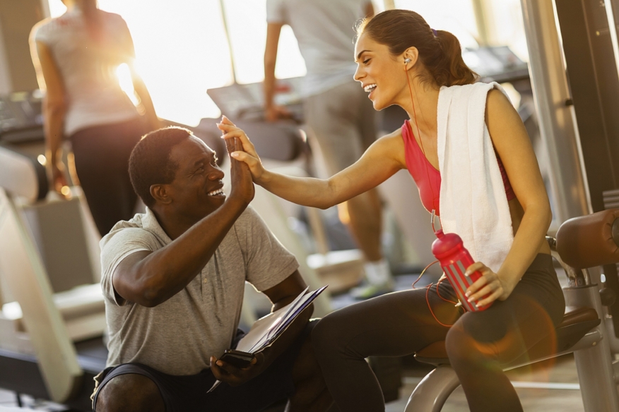 Personal trainer celebrating a victory with a high-five with his female client.