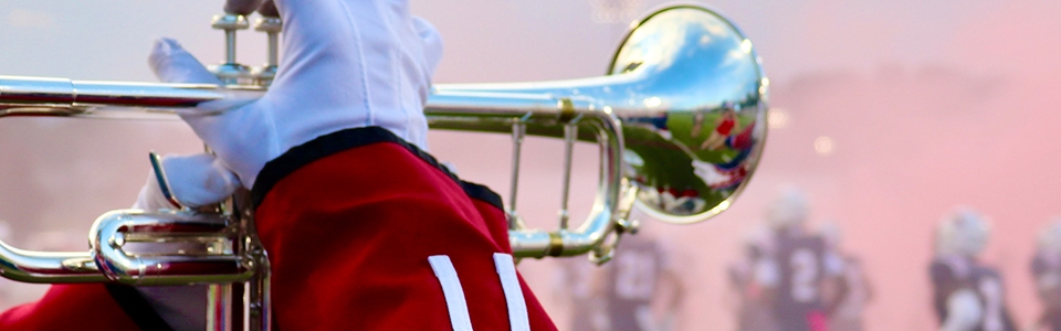 A band student plays the trumpet at a football game. 