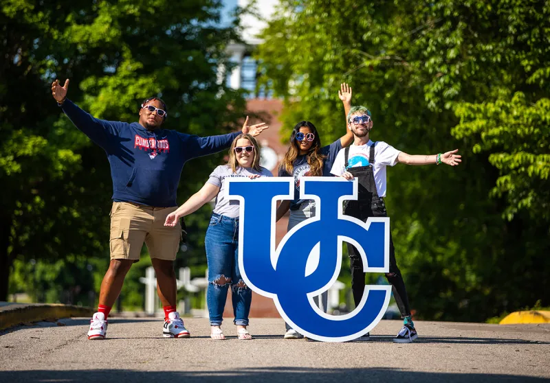 University of the Cumberlands student pose on campus with a UC sign. 