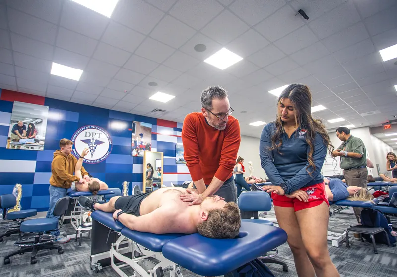 A DPT instructor shows a student proper techniques in the classroom. 