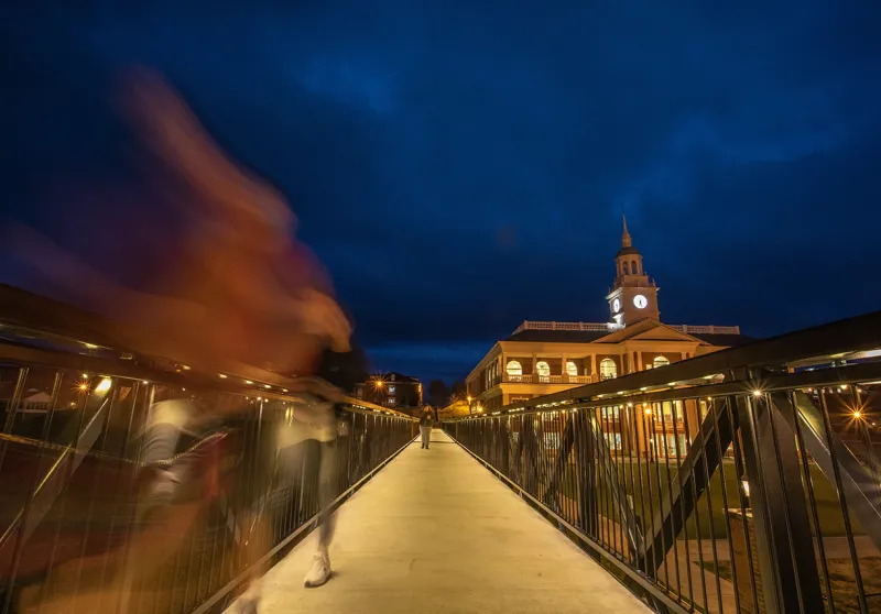 A student walks across the viaduct at night. 