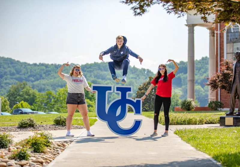 Student leaping over UC sign