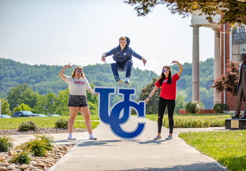 Student leaping over UC sign