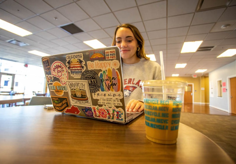 Young woman using laptop that's covered in stickers