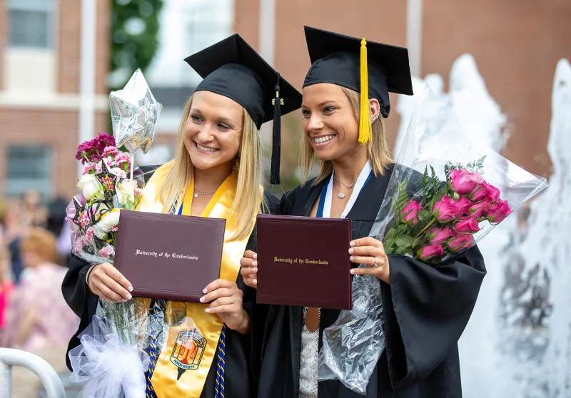 Graduates pose with their diplomas in front of the fountain