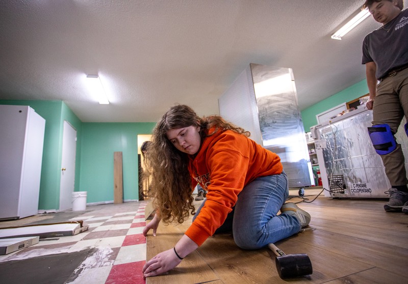 A volunteer helps install flooring on a Mountain Outreach project site 