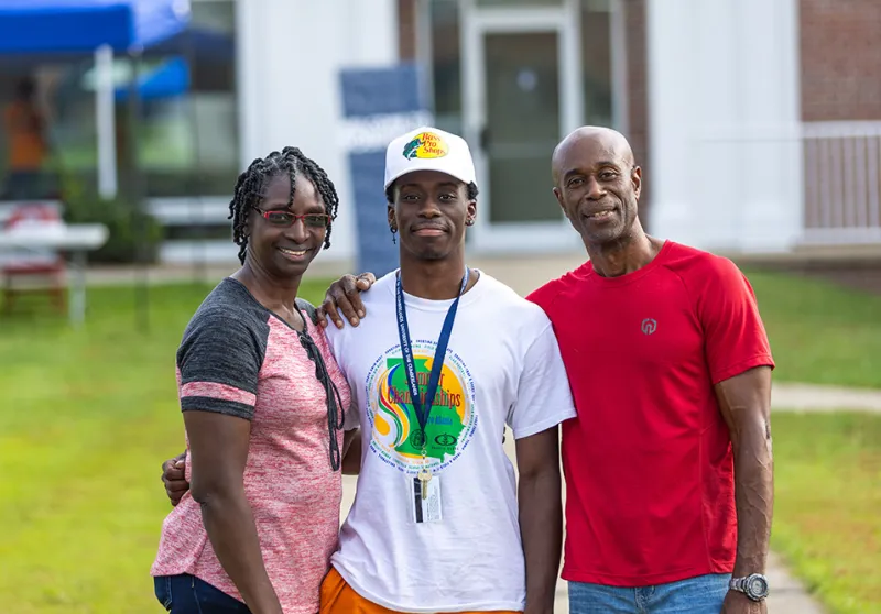 Parents standing with son, posing for picture.