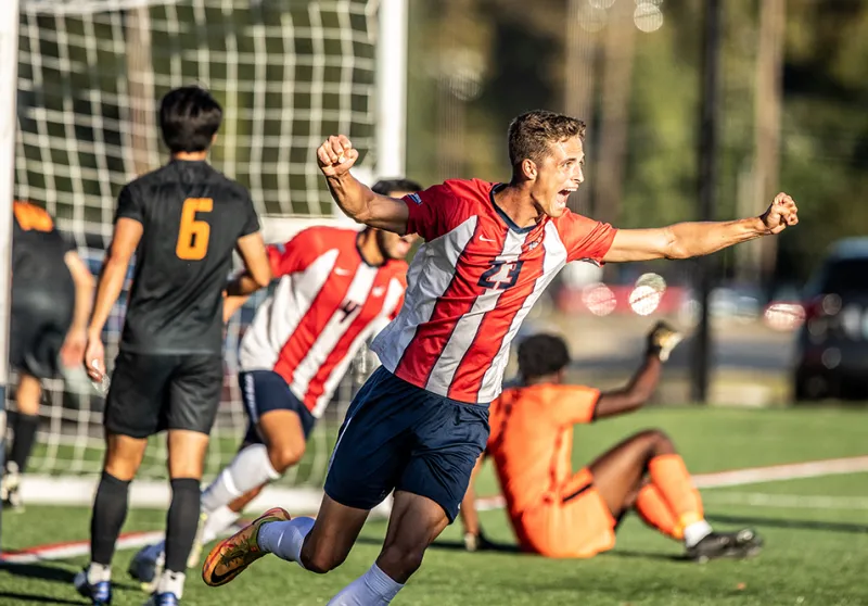 Men's soccer players cheer after scoring a goal
