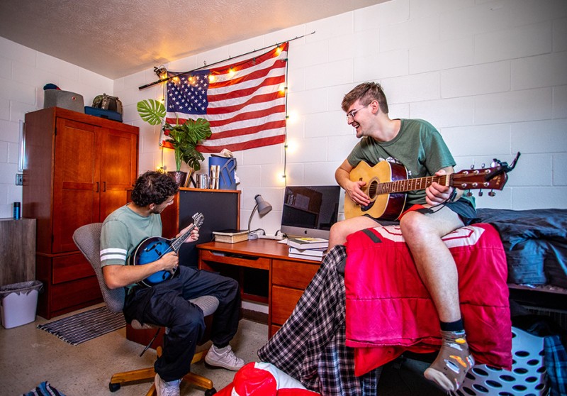Two guys playing guitar in a dorm room