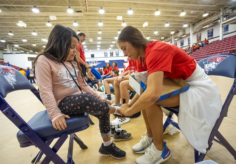 A Cumberlands student helps a local child try on new shoes