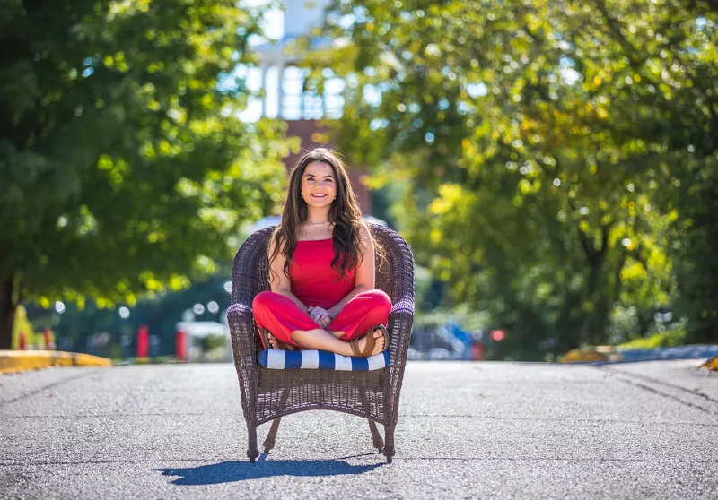 A student poses on campus in front of the admissions office