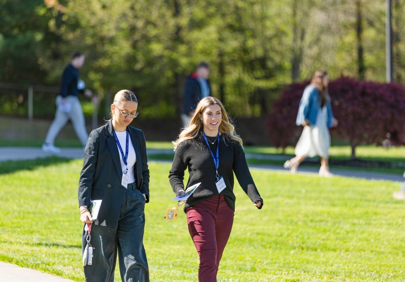 Two female business students walk across campus during the annual business forum. 