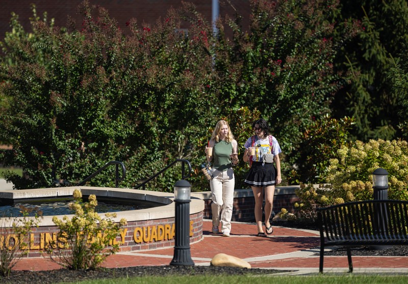 Two female students are walking in the quad while talking. 
