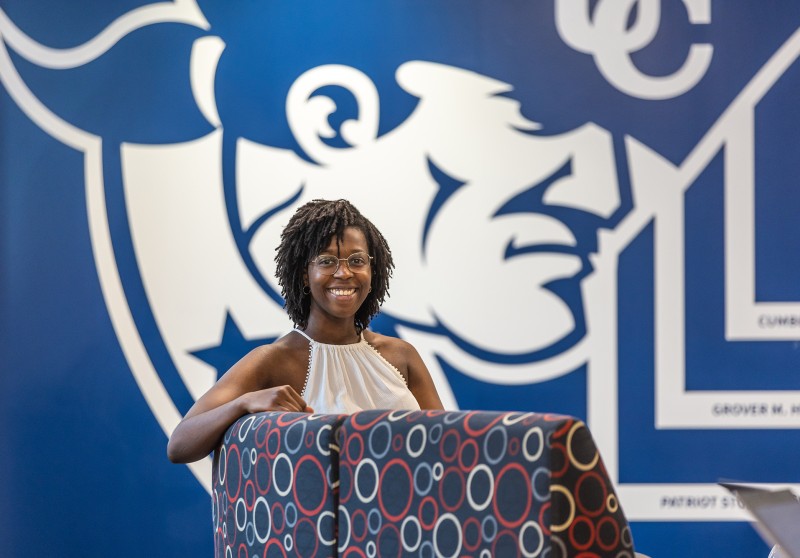 A female student sits in a chair in front of a wall with the Cumberlands logo in the student success center. 
