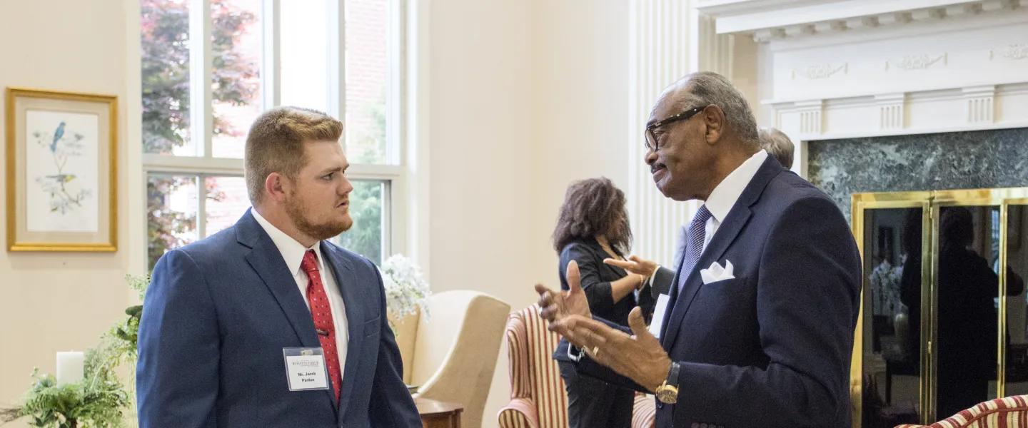 An older man speaking to a young adult