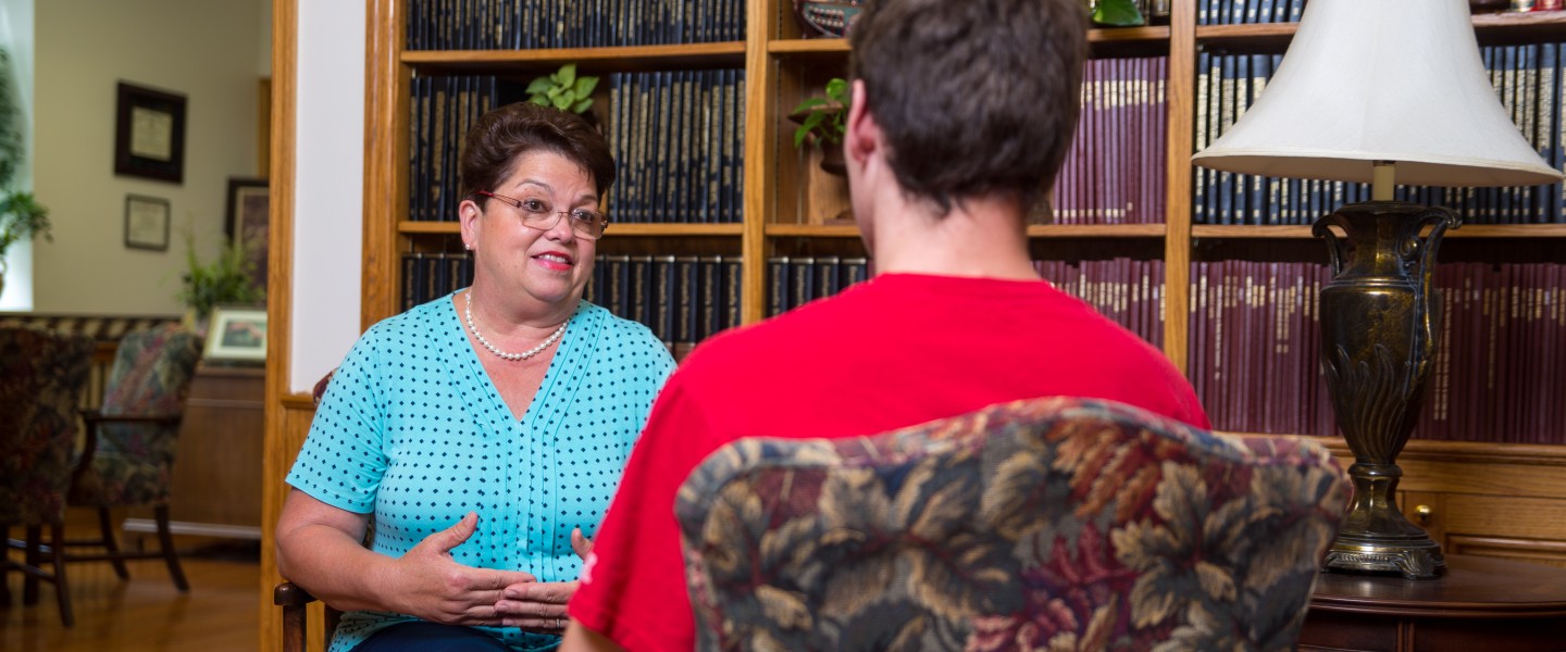 A woman speaking with a young man
