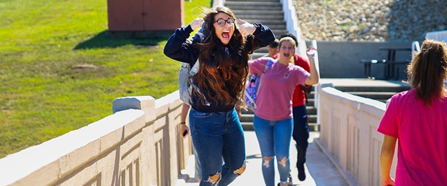 A student jumping for a picture while on a boardwalk
