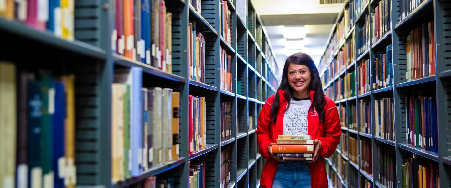 Student standing next to bookshelves
