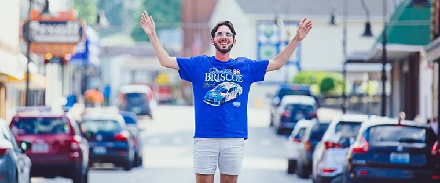 Student posing for a picture with both arms up